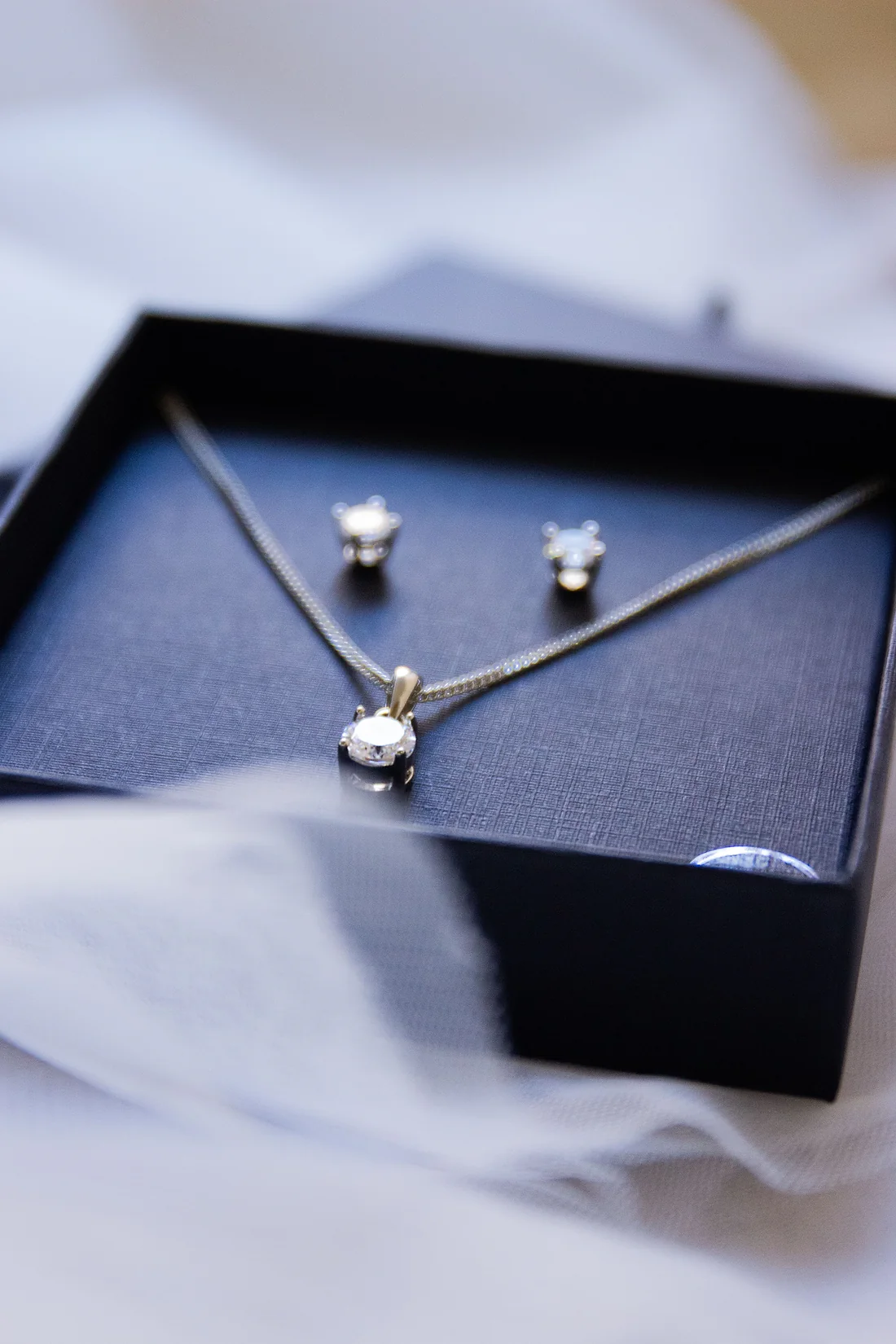 Diamond solitaire pendant and stud earrings in a black gift box