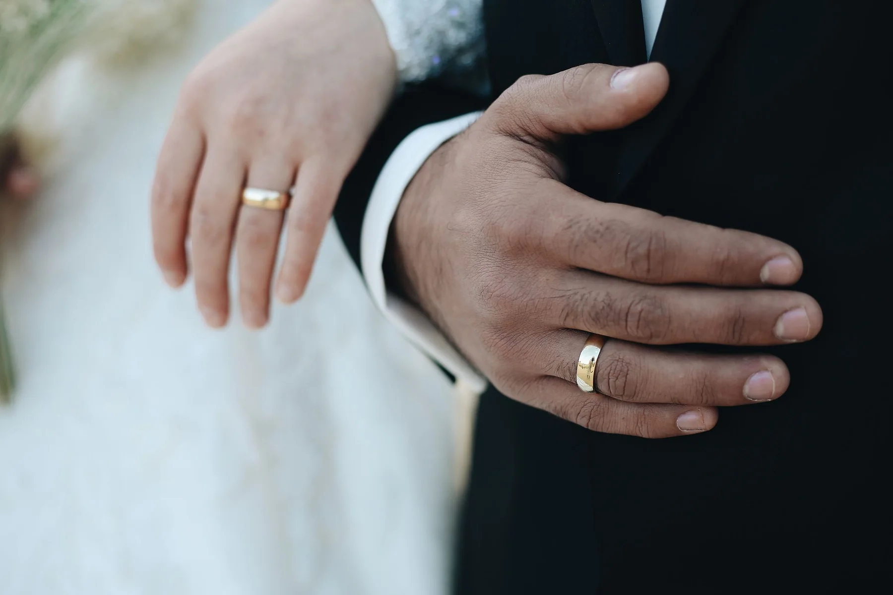 Bride and groom wearing matching gold wedding bands