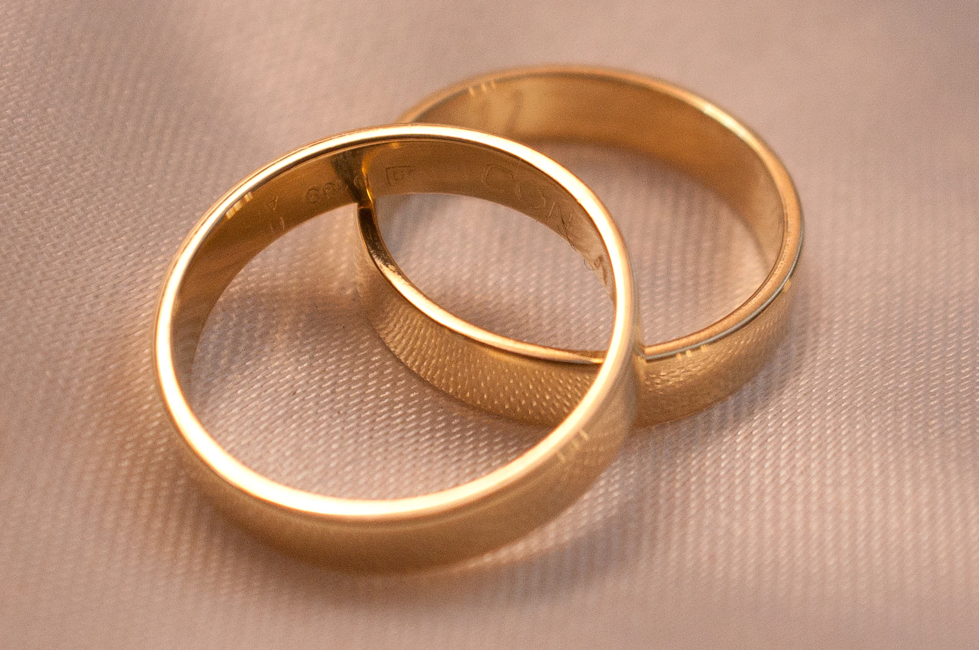 Two gold wedding bands resting on soft cream fabric